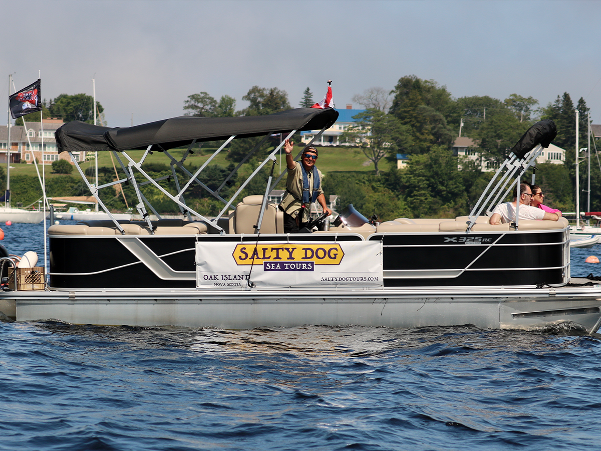 Salty Dog Sea Tours boat cruising past the wooded shoreline of Oak Island